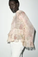 Camisa de cuello subido y manga larga con estampado floral en tonos rosa y verde. Detalle de volantes en cuello, mangas y ruedo. Cierre en espalda con abertura y botones.