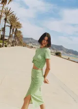 Falda midi de tiro alto con estampado a cuadros vichy en verde y blanco, con frunce lateral y abertura en el ruedo.