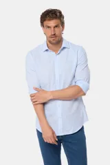 Camisa de manga larga, color celeste con finas rayas blancas, confeccionada en una mezcla de lino y algodón. Presenta un corte slim fit y no tiene bolsillo.