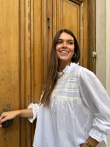 Camisa negra de mangas largas con cuello fruncido y detalle de bordado en el pecho.