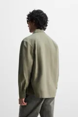 Sobrecamisa verde militar de algodón con estructura canvas, corte relaxed fit, cuello solapa, manga larga con puños abotonados, bolsillos frontales de plastrón con solapa, efecto lavado y cierre frontal con botones.