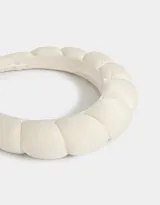 Vincha rígida color blanco crudo, recubierta de tela satinada con diseño acolchado.