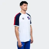 Remera de algodón blanca con mangas cortas ranglan azul marino con una franja roja en el hombro. Tiene el logo de Umbro bordado en el pecho y el escudo del Club Nacional de Football.