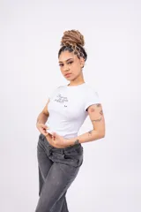 Remera blanca ajustada de jersey con lycra, con mangas cortas y estampado frontal con la frase "Break with the limits of reality" en letras cursivas negras.