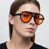 Lentes de sol de aviador con montura negra y lentes naranjas. Fabricados con materiales bio-based G850 y patillas de propionato de celulosa. Cuentan con protección UV400 y lentes TAC polarizadas con recubrimiento antiscratch y superhydrophobic.