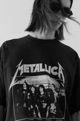Remera negra de algodón con estampado del logo de Metallica y la imagen de la banda Damage Inc. 1986. Corte oversized con cuello redondo ribeteado, hombros caídos y bajo recto.