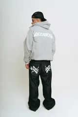 Pantalón de jean negro de corte baggy, con estampado de trigramas blancos en los bolsillos traseros.