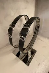 Cinturón de cuero negro con hebilla de metal plateado con forma de serpiente.
