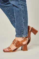 Sandalias de cuero color champagne, con punta cuadrada, tira ancha sobre el empeine y tira al tobillo con hebilla metálica. Taco cuadrado de 7 cm.
