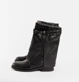 Bota corta de cuero color marrón con suela de goma negra, taco de madera de 3cm y caña de 25cm. Presenta una correa con hebilla y tachas pequeñas alrededor del tobillo.