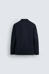 Blazer azul marino de corte regular fit, confeccionada en tejido de algodón con elasticidad. Sin forro interior, con cuello de solapas de muesca, manga larga con puños abotonados, bolsillos de solapa en la cadera, bolsillo interior, aberturas en la espalda y cierre frontal con botones.