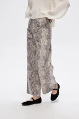 Pantalón jean ancho con estampado de piel de serpiente en tonos beige y gris.