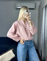 Camisa blanca de mangas largas con puños abullonados y detalles de encaje en cuello, mangas y ruedo.