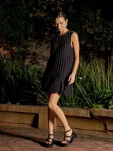 Minivestido negro con lurex, sin mangas, corte recto y volado en el ruedo.