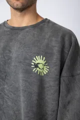 Buzo de cuello redondo y corte oversize en tela friza, color gris con efecto acid wash. Presenta un estampado frontal en color verde lima con un diseño abstracto.