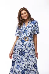 Vestido midi de algodón con estampado floral en tonos azul y blanco, corte camisero, cuello clásico, mangas cortas y cinturón con hebilla redonda de madera.
