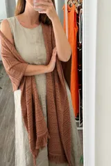 Ruana tejida color marrón terracota, con diseño calado de puntos y terminaciones con flecos.