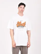 Remera blanca de corte oversized con estampado frontal de letras en color naranja y negro.