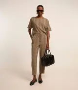 Pantalón fluido de cintura alta confeccionado en crepé con elástico y lazo en la cintura, bolsillos, recortes y estampado de lunares diferenciado.