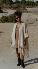 Ruana color crudo, tejida a mano en Uruguay con hilado serido 50% algodón y 50% acrílico. Tiene flecos largos en el ruedo.