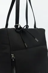 Bolso tote negro de nylon con diseño acolchado, asas largas para llevar al hombro, cierres metálicos laterales y detalle de cordón.