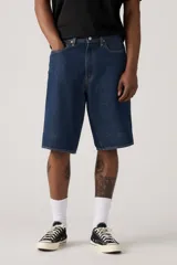 Bermuda de jean azul oscuro, corte holgado y largo hasta la rodilla.