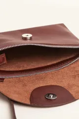 Cartera tipo sobre de cuero vacuno, con solapa frontal, cierre y broche magnético. Incluye correa larga ajustable y extraíble para usar como bandolera.