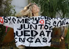 Sweater tejido a mano en 100% algodón, con diseño geométrico en blanco, negro, naranja y rosa. Corte holgado y flecos en el ruedo.