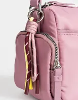 Bandolera de tela deportiva color lila, con correa regulable, bolsillo frontal con cierre, bolsillos laterales con cierre y charm decorativo.
