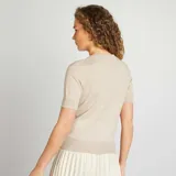 Sweater de punto color beige de manga corta y cuello redondo.