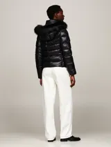 Campera puffer negra de nailon con relleno de plumón, capucha fija con ribete extraíble de pelo sintético, cuello alto, cierre de cremallera, bolsillos laterales con cremallera y parche con el logo de Tommy Hilfiger en la manga.