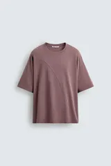 Camiseta color marrón con costura curva en el frente, corte holgado, cuello redondo y mangas cortas.
