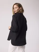 Camisa blanca de algodón con cuello clásico, cierre frontal con botones y mangas largas. Presenta bordados calados con motivos florales en la parte superior.