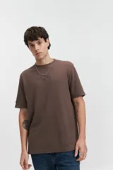 Remera marrón de manga corta con cuello redondo, textura acanalada y lettering estampado en el pecho.