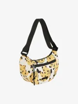 Bolso tipo bandolera con estampado de bananas amarillas y negras sobre fondo blanco. Tiene correa negra ajustable y cierre superior con cremallera.