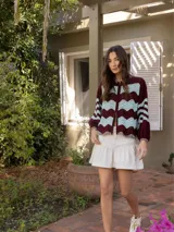 Campera tejida con diseño de ondas en color borgoña y celeste. Tiene cierre frontal y mangas largas con puños acanalados.