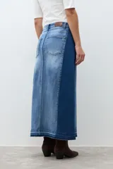 Falda larga de jean de tiro alto, con lavado medio y tajo frontal profundo. Presenta un diseño bicolor con paneles de denim de tonos ligeramente diferentes.