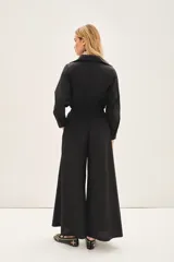 Mono negro con corte palazzo, mangas largas y lazo en la cintura.