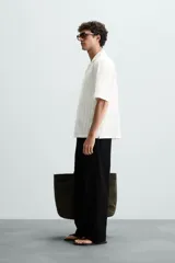 Camisa de calce relajado confeccionada en tejido jacquard de mezcla de algodón y viscosa. Presenta cuello bowling, manga corta, aberturas laterales en el bajo y cierre frontal con botones.