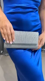 Cartera de mano plateada con textura brillante y diseño plisado.