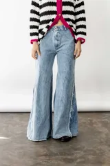Pantalón de jean celeste con lavado ácido, corte wide leg, tiro medio, godets y ruedo desflecado.