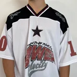 Camiseta blanca de estilo deportivo con cuello en V y mangas cortas. Presenta detalles en negro en los hombros y cuello, y un estampado con una estrella y la inscripción "Power Velocity". Tiene números en las mangas.