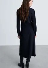 Vestido midi camisero color azul marino, con botones dorados en el frente, mangas largas con puños abotonados, corte entallado y falda evasé.