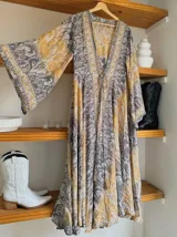 Kimono largo de seda con estampado floral en tonos verde, marrón y beige. Tiene mangas amplias y corte cruzado con lazo ajustable en la cintura.