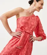 Vestido midi color salmón con bordado calado, de un hombro, manga larga abullonada y lazo en la cintura.
