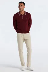 Sweater de punto color bordó con cuello polo y cierre de media cremallera. Presenta detalles de rayas blancas en el cuello y los puños, manga larga y logo bordado en el pecho.