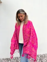 Pañuelo fucsia con estampado de arabescos en tonos naranja y violeta, con flecos en el borde.