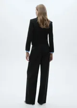 Blazer corto negro con cuello de solapa de pico, cierre frontal con botones y bolsillos de parche.