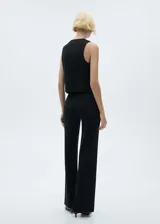 Chaleco negro con cuello en pico, diseño crop y cierre frontal con botones.