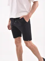 Bermuda negra con textura acanalada horizontal, corte a la rodilla y cintura con cordón ajustable.